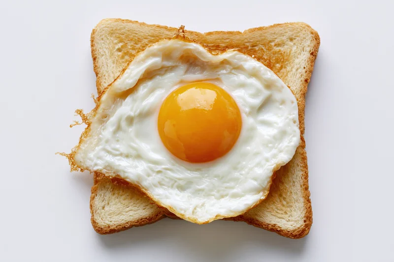 Single fried egg sunny-side-up resting on a square slice of toast