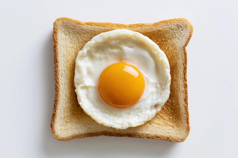 Single fried egg sunny-side-up resting on a square slice of toast
