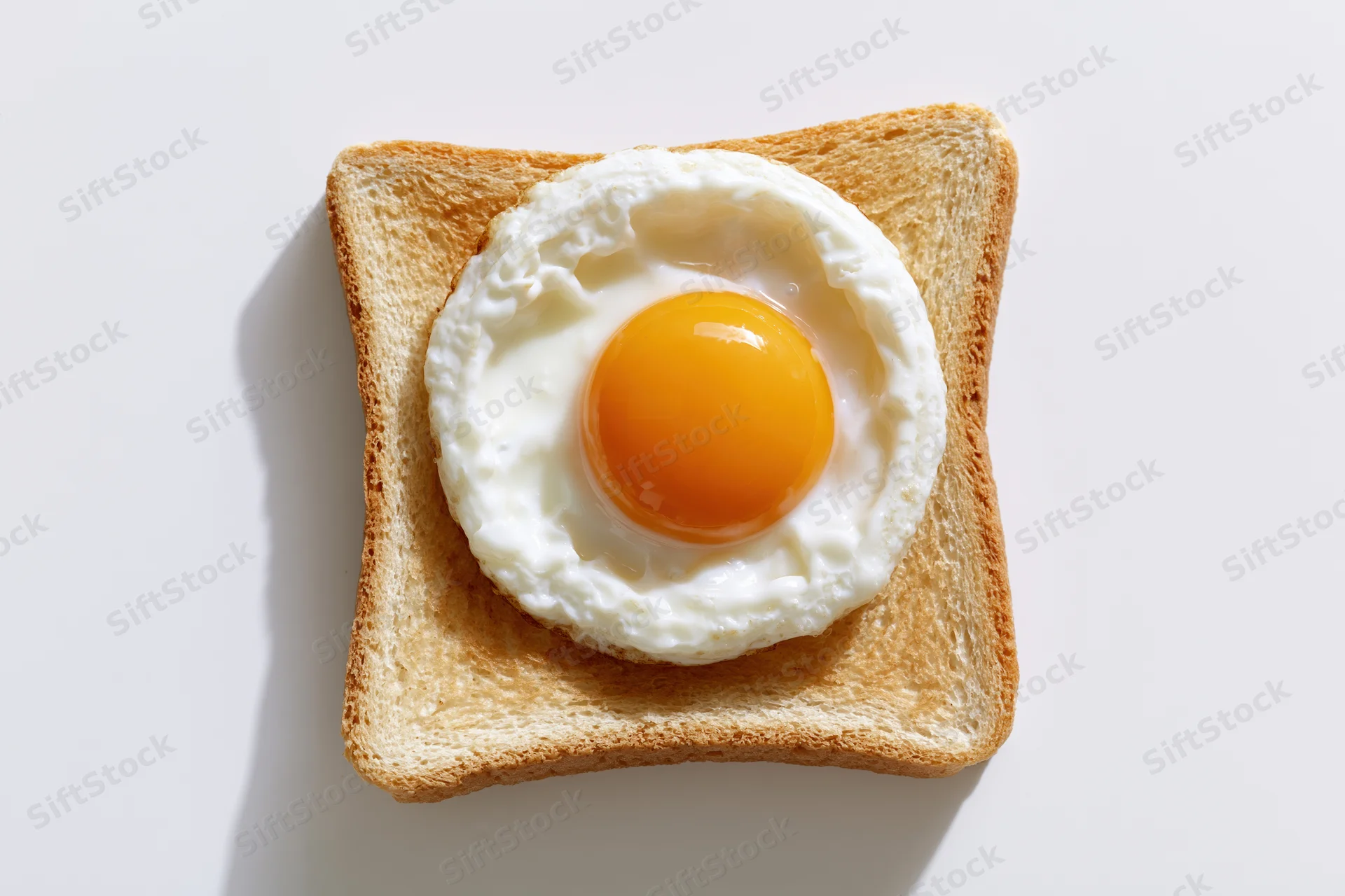 Single fried egg sunny-side-up resting on a square slice of toast