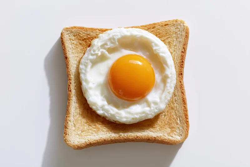 Single fried egg sunny-side-up resting on a square slice of toast