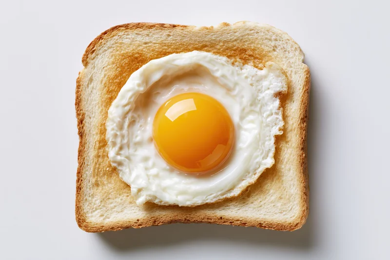 Single fried egg sunny-side up resting on a square slice of toast