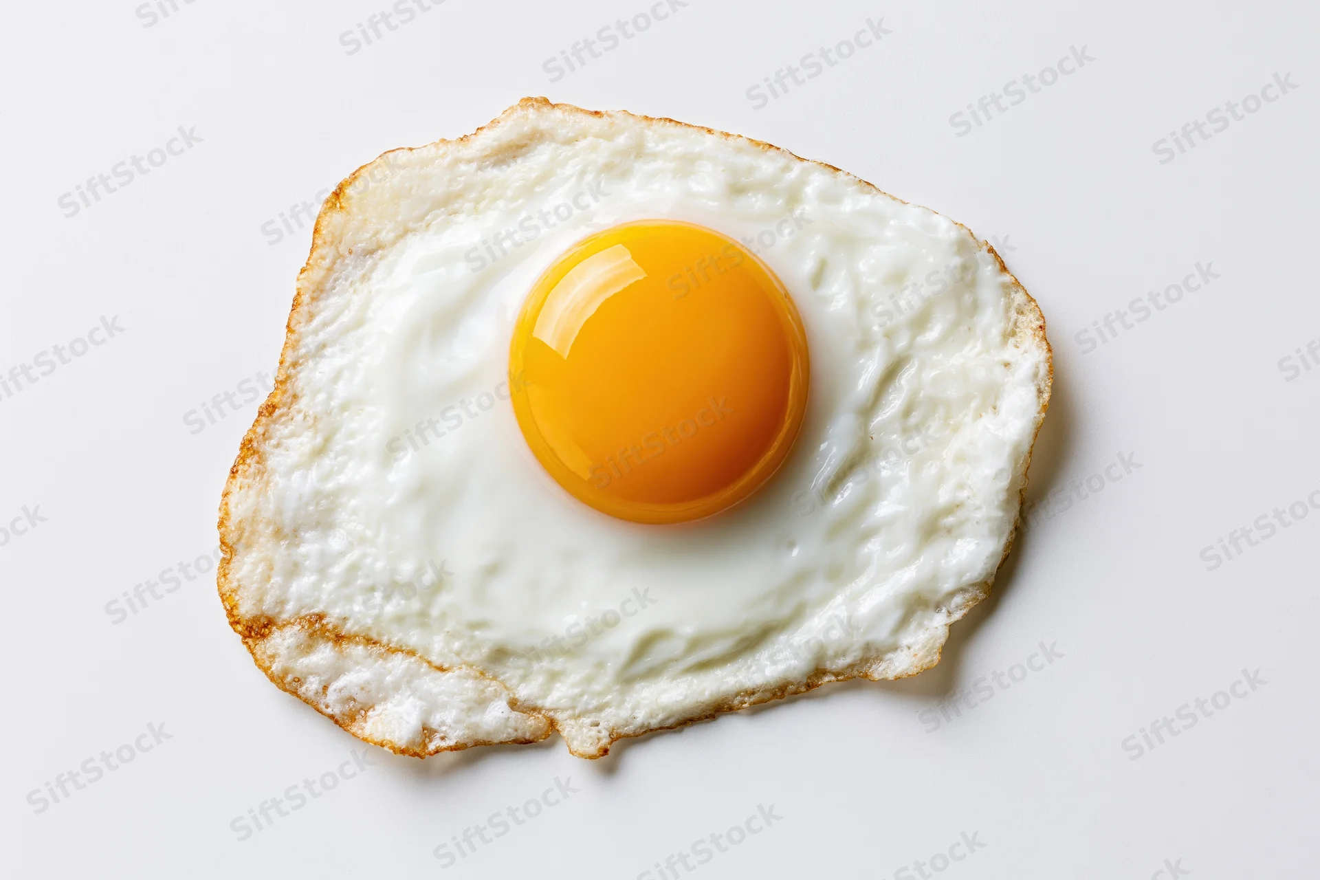 Single fried egg sunny side up viewed from directly overhead on white surface