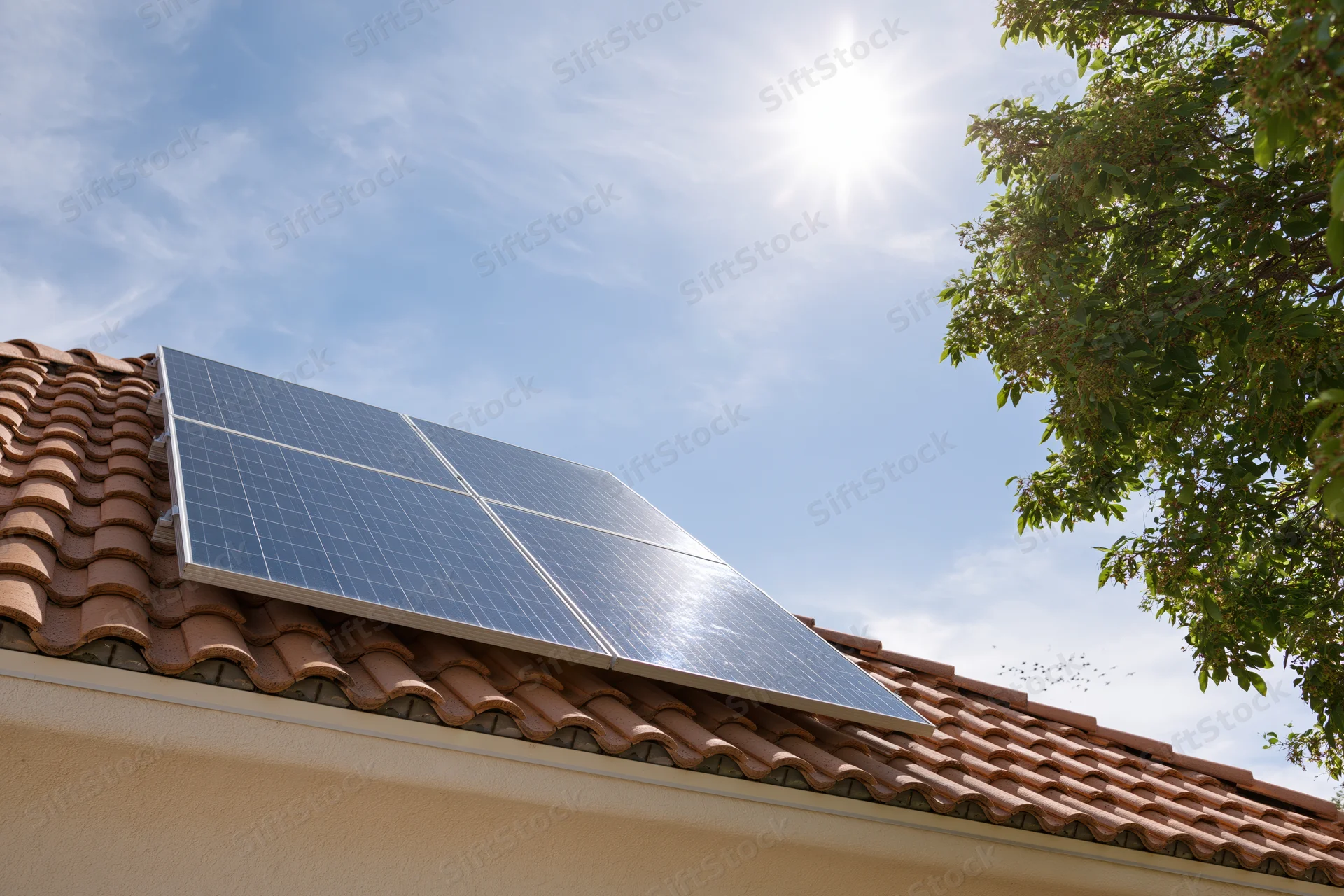 Solar panels installed on a terracotta-tiled residential roof under bright sunlight