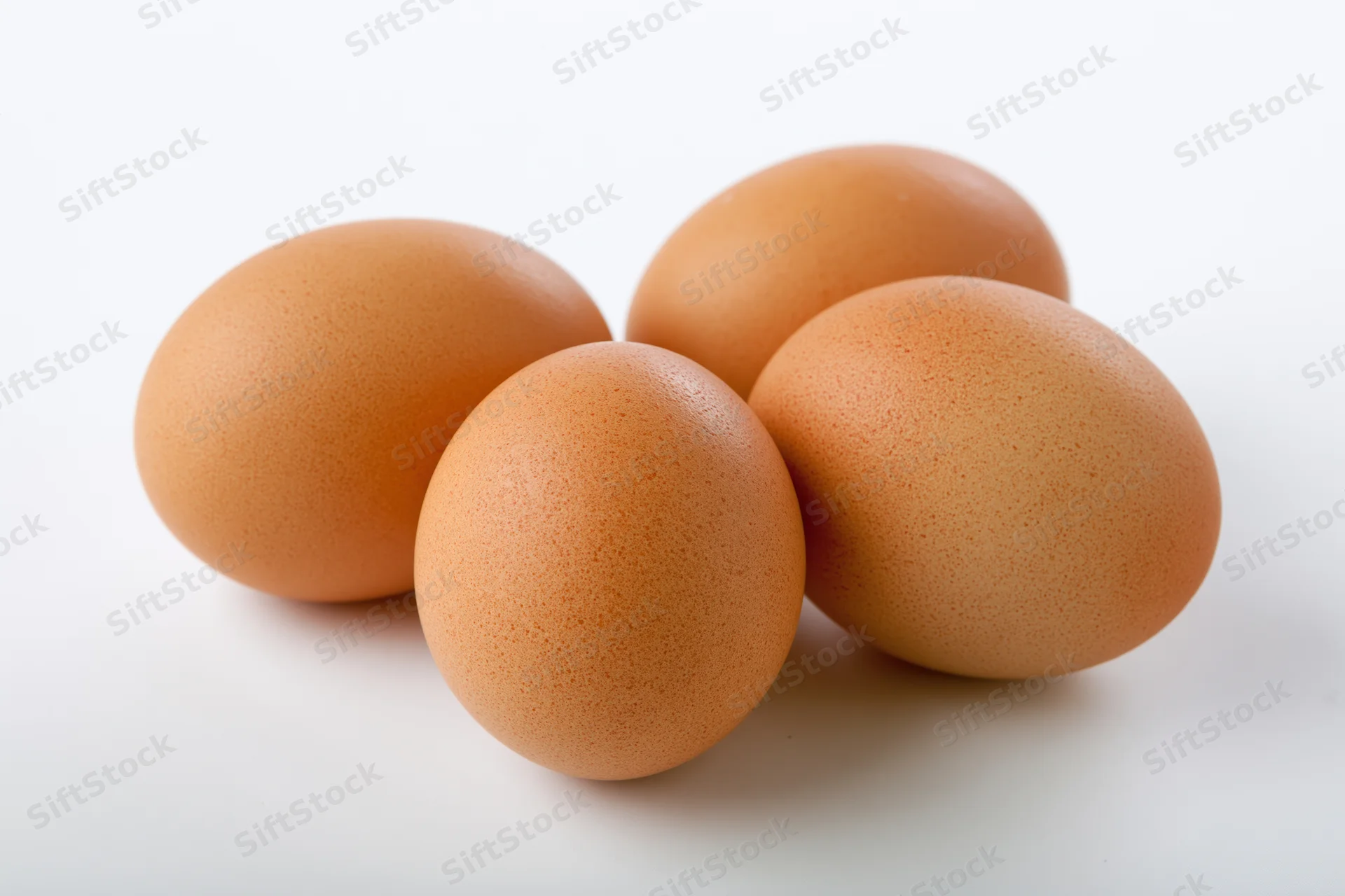 Four brown chicken eggs grouped together on a white surface with copyspace