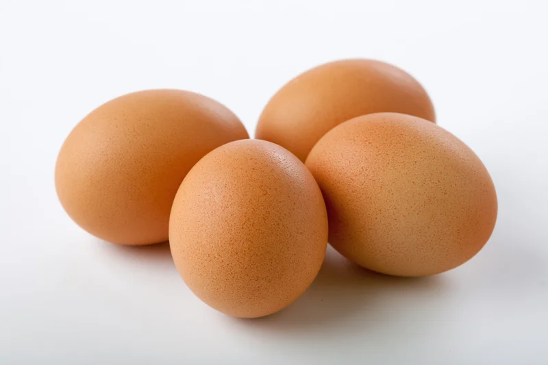 Four brown chicken eggs grouped together on a white surface with copyspace