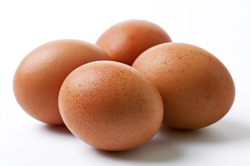 Four brown chicken eggs grouped together on a white surface with soft shadows