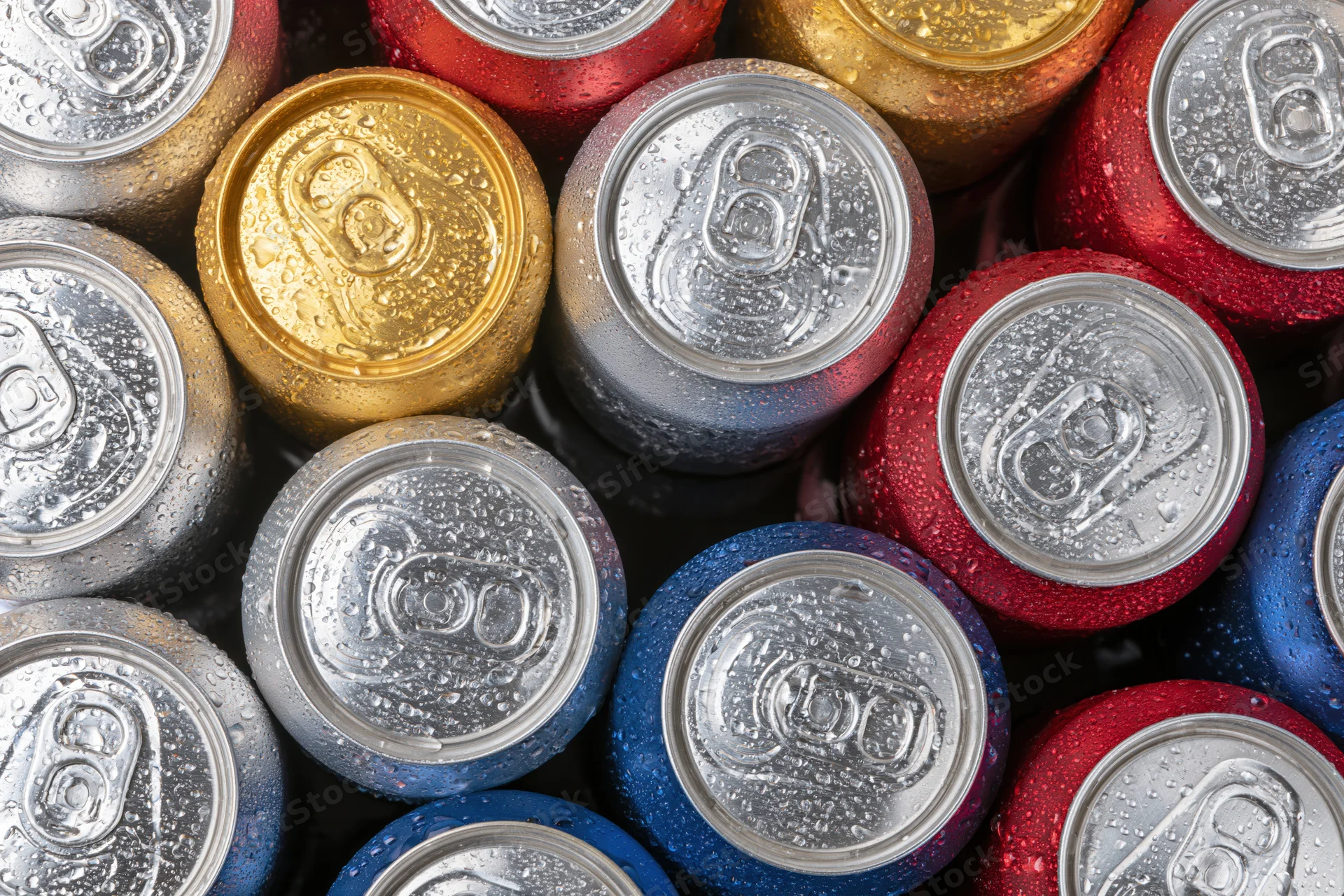 Tops of aluminum beverage cans packed tightly together, showing condensation and multicolored surfaces