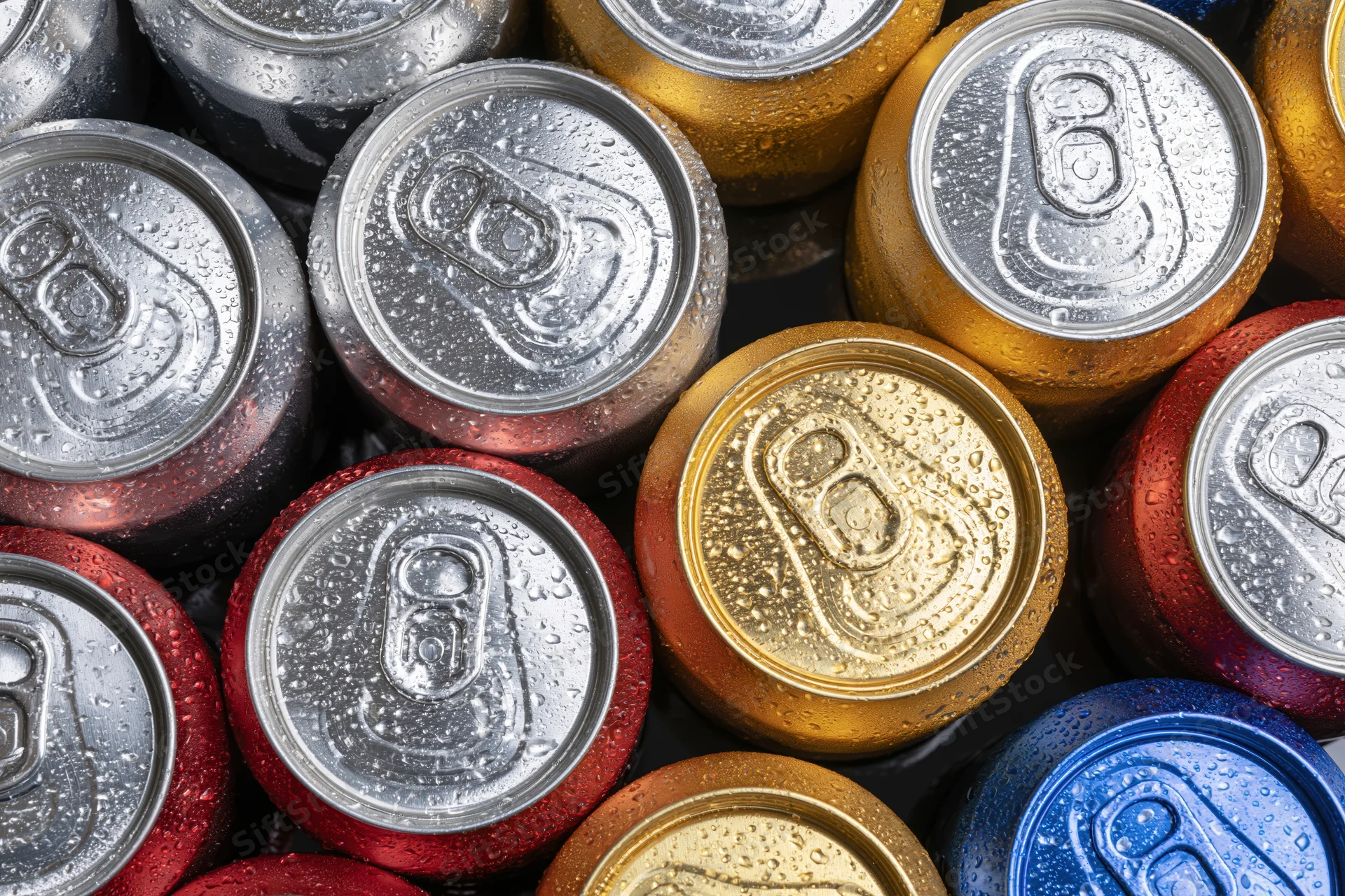 Tops of aluminum beverage cans packed tightly together, showing condensation and multiple colors