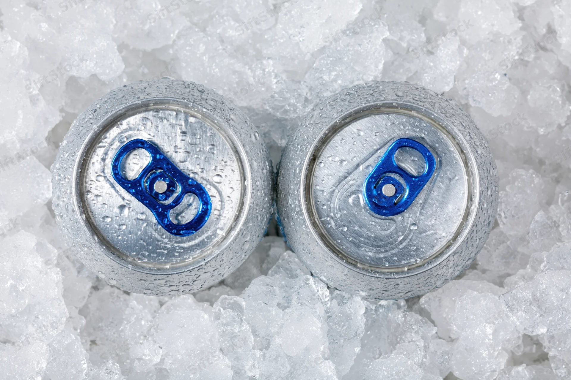 Two aluminum beverage cans with blue pull tabs resting in crushed ice