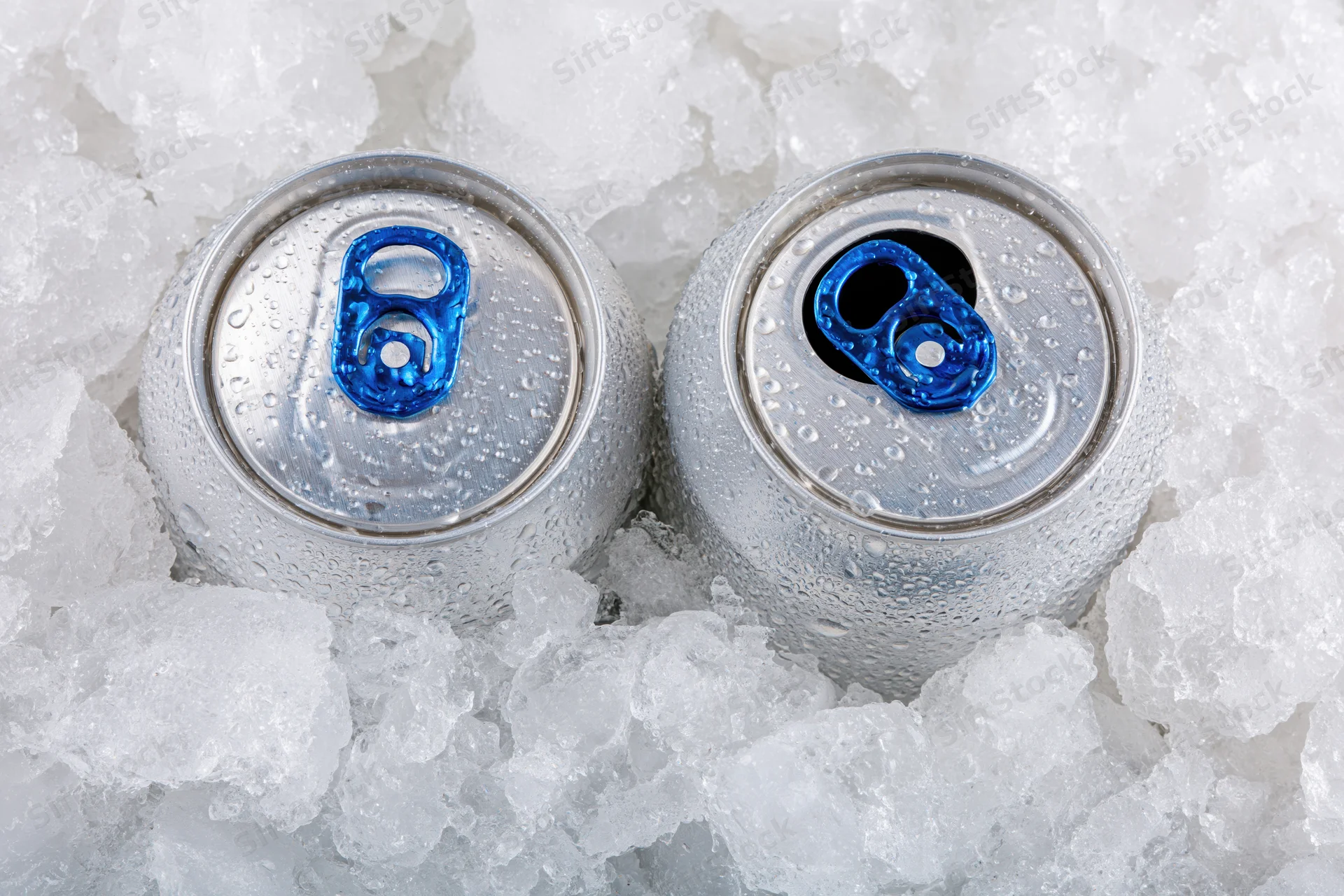 Two aluminum beverage cans with blue pull tabs resting in crushed ice