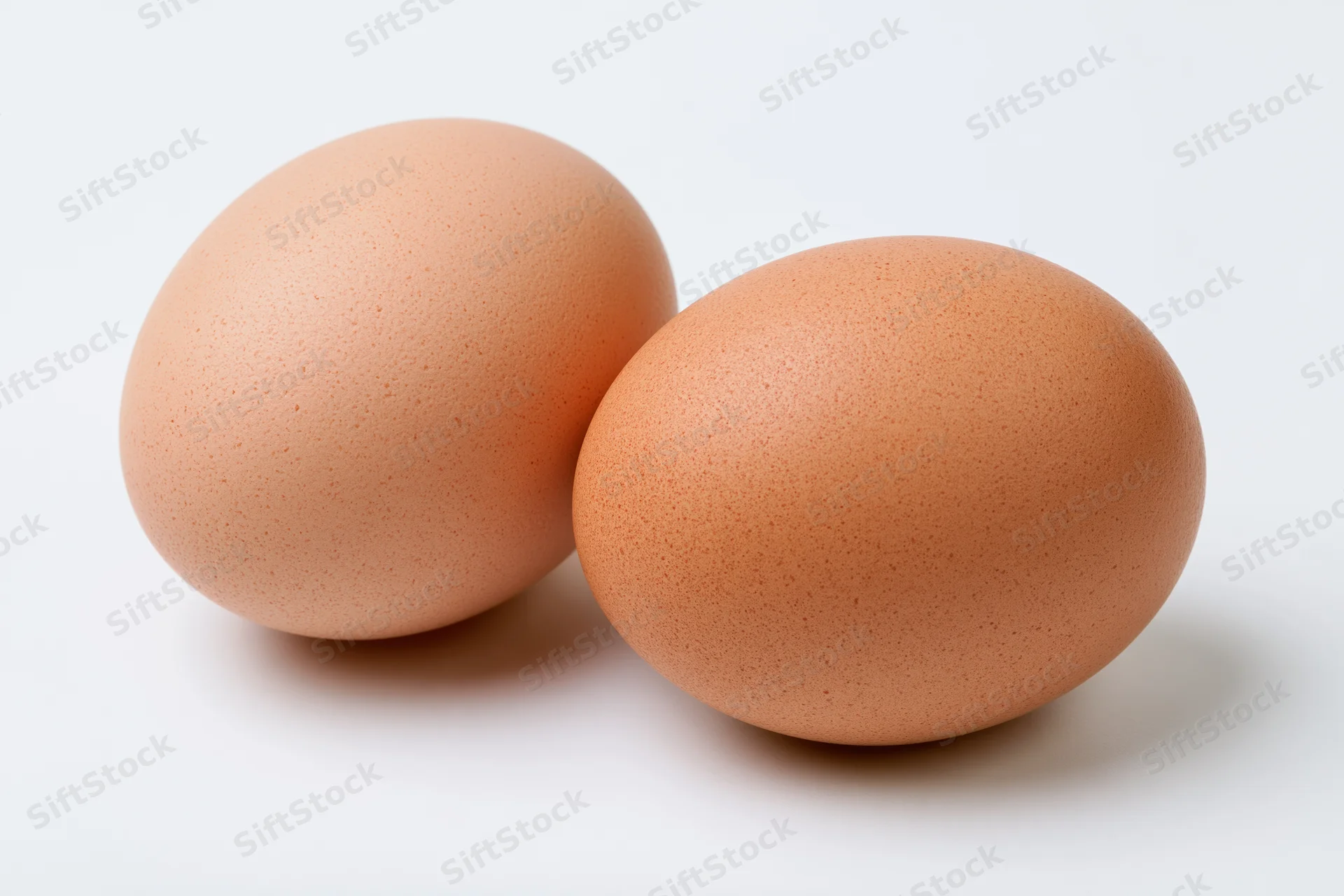 Two brown chicken eggs resting side by side on a pure white surface
