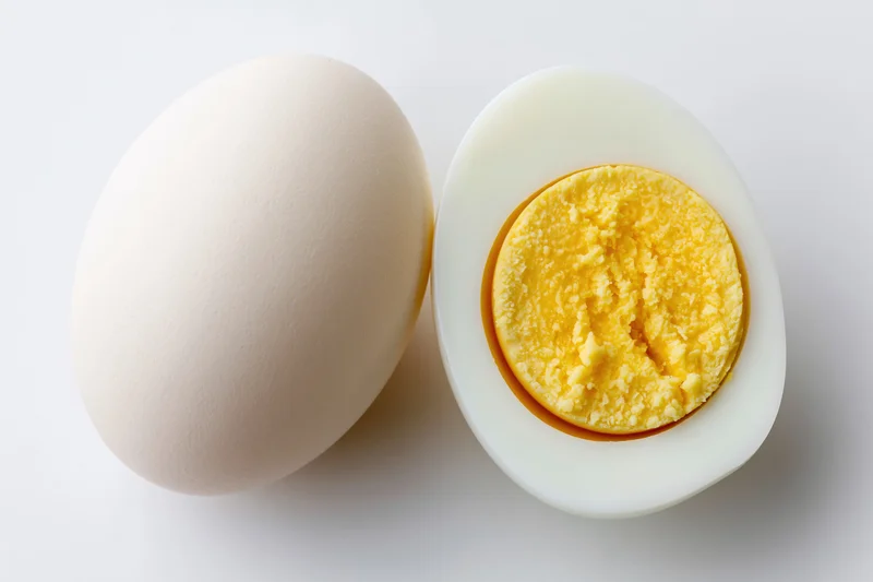 Whole and halved hard-boiled egg on white background with copyspace