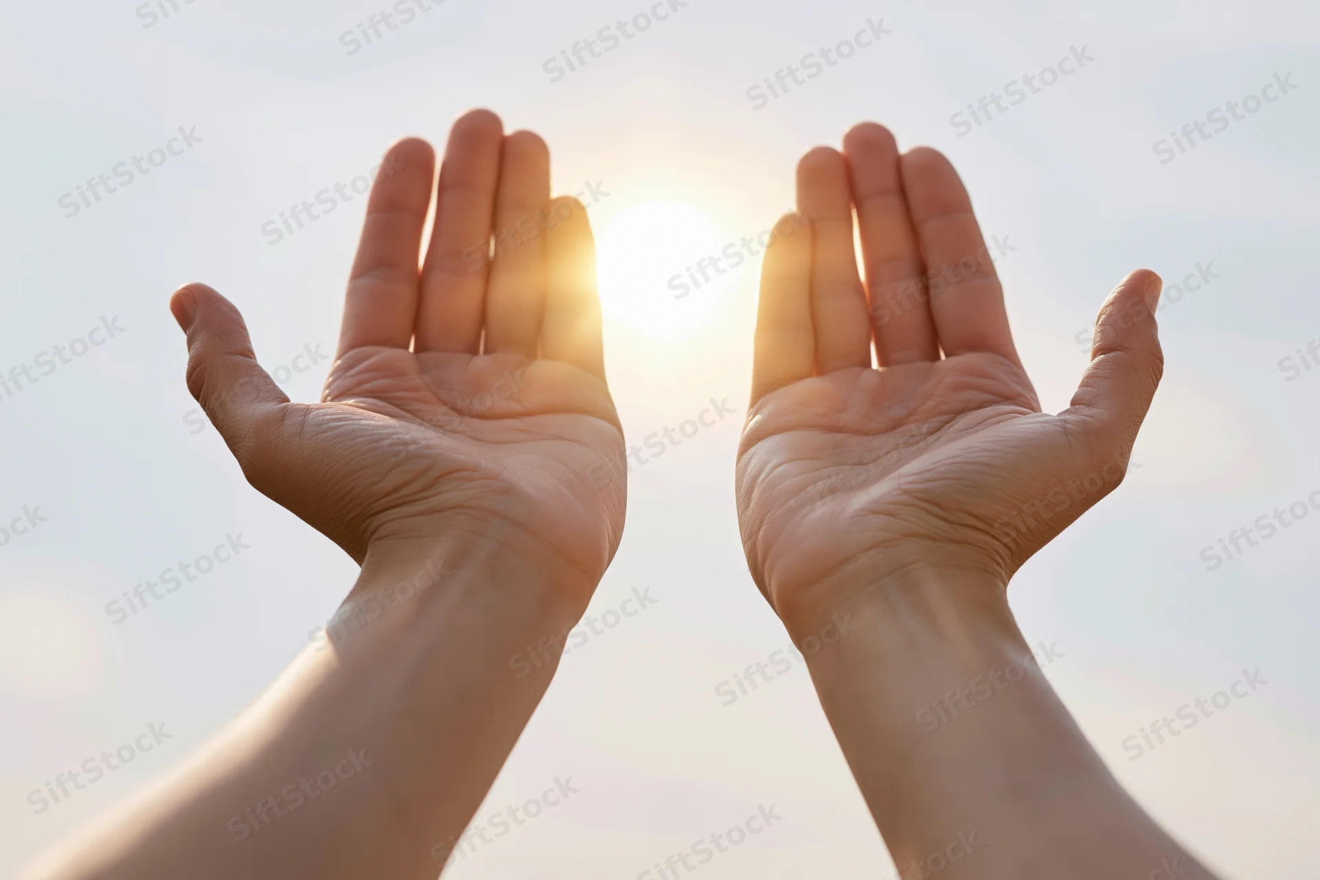 Open hands raised upward toward a bright glowing sun in the sky