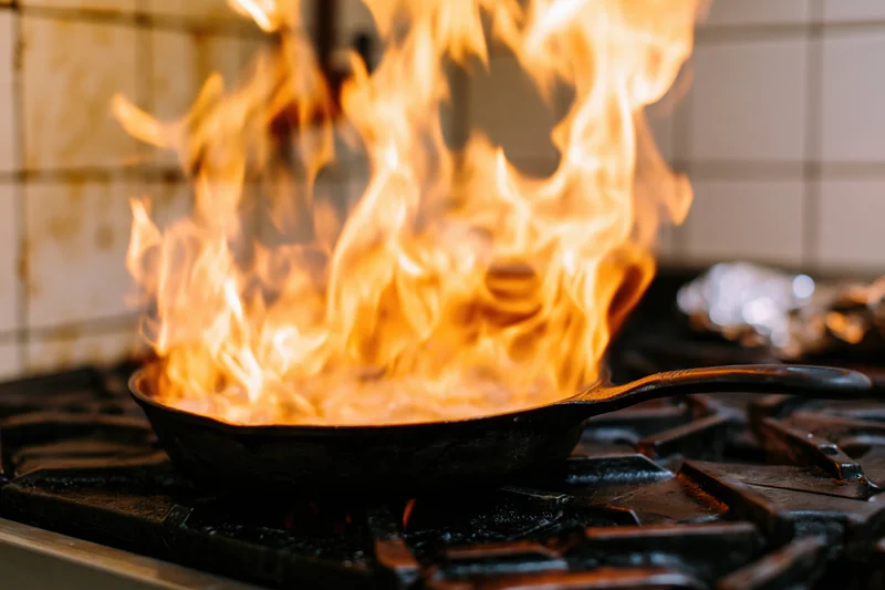 Cast iron skillet with tall flames on gas stove in kitchen