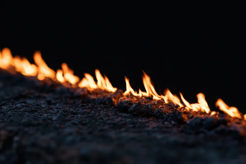 Flames burning along a dark textured surface in closeup view