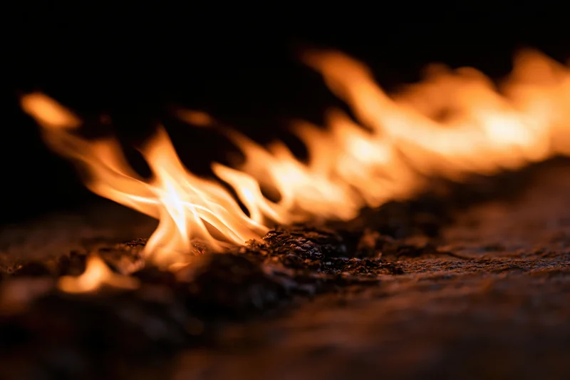Flames burning along a dark textured surface in close-up view
