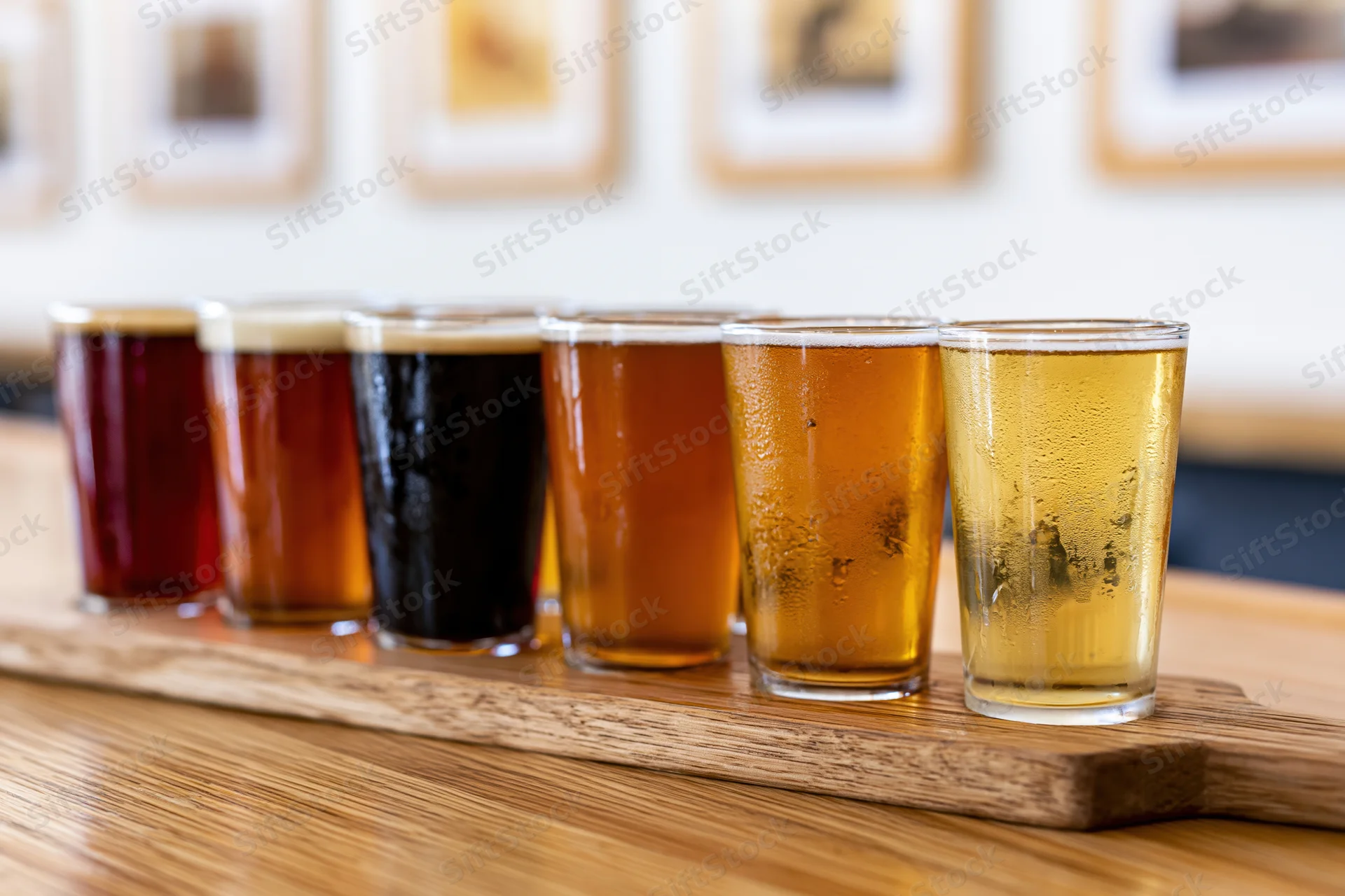Eight craft beers in small glasses arranged on a wooden tray on a table