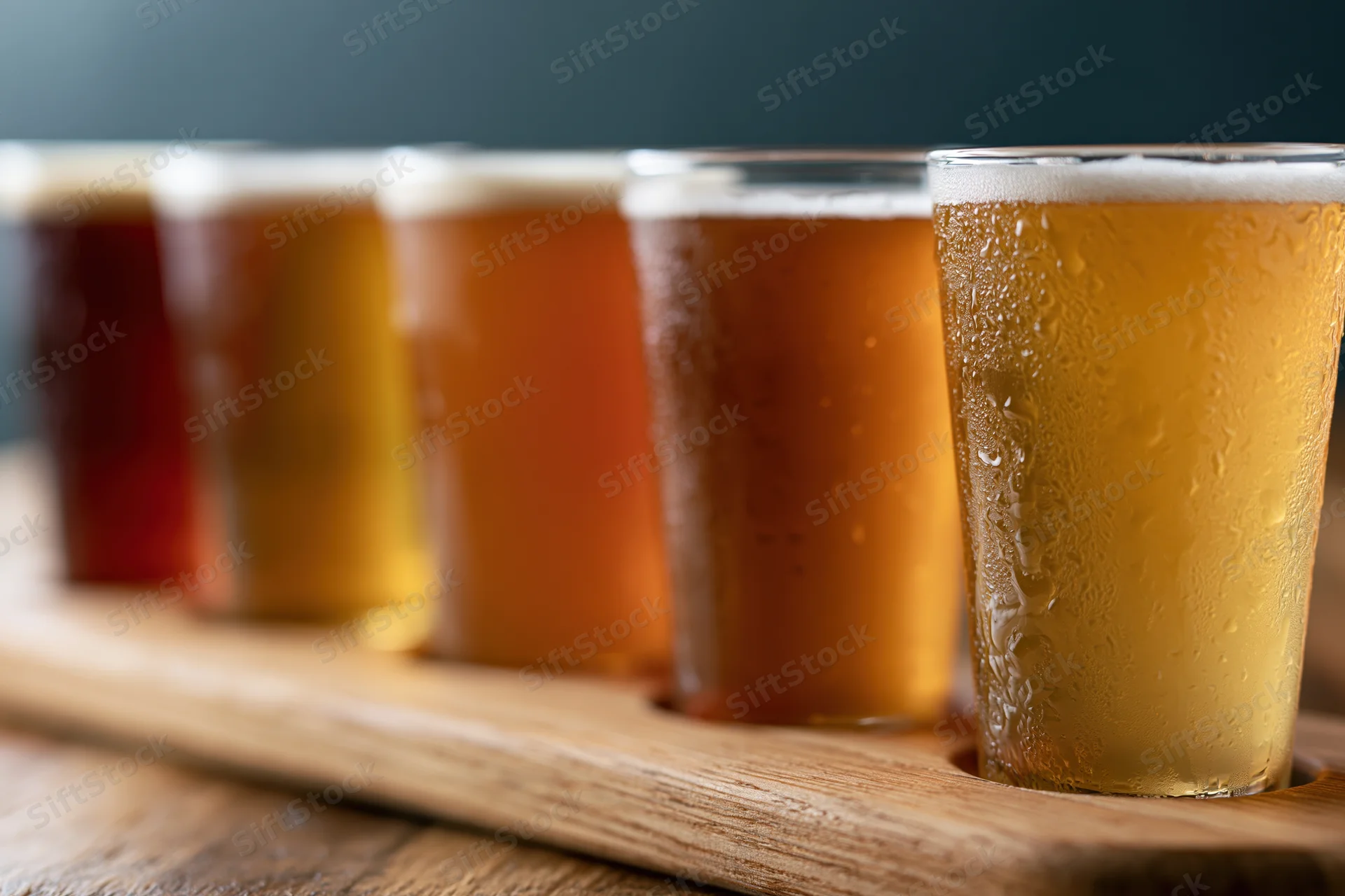 Five craft beers in small glasses arranged in a row on a wooden tray