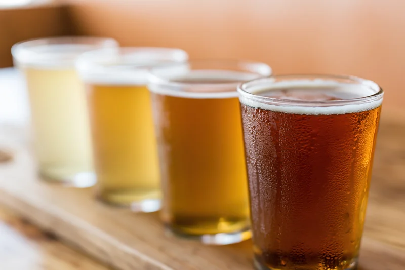 Four craft beers in pint glasses arranged in a row on a wooden tray