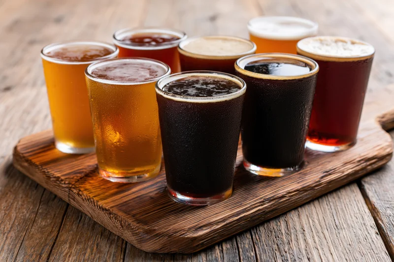 Seven craft beers in glasses arranged on a wooden tray