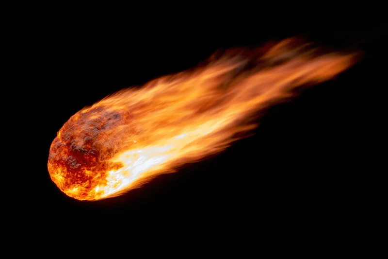 Glowing meteor with fiery trail moving diagonally across dark space