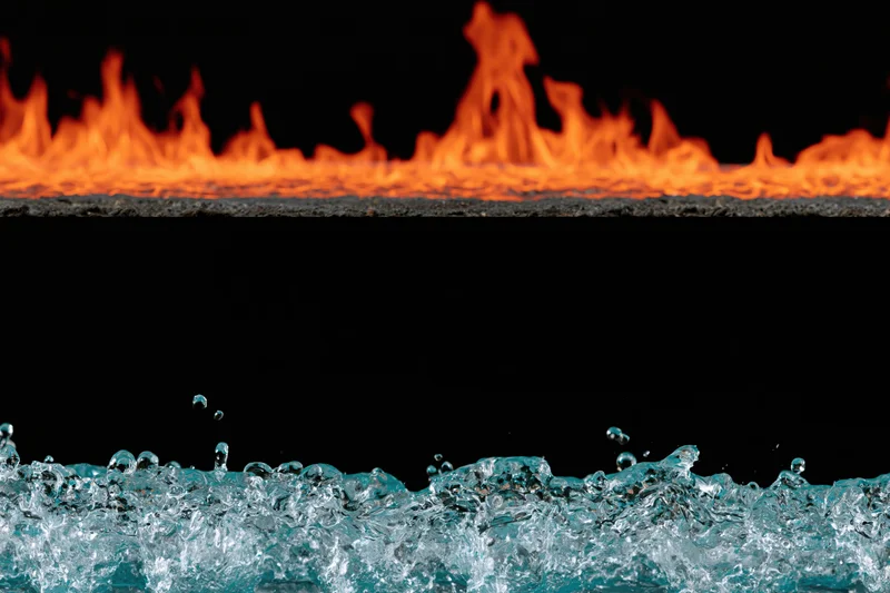 Fire flames above splashing water against black background