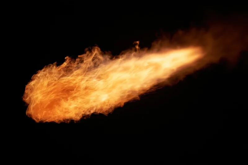 Horizontal jet of fire streaking across a black background