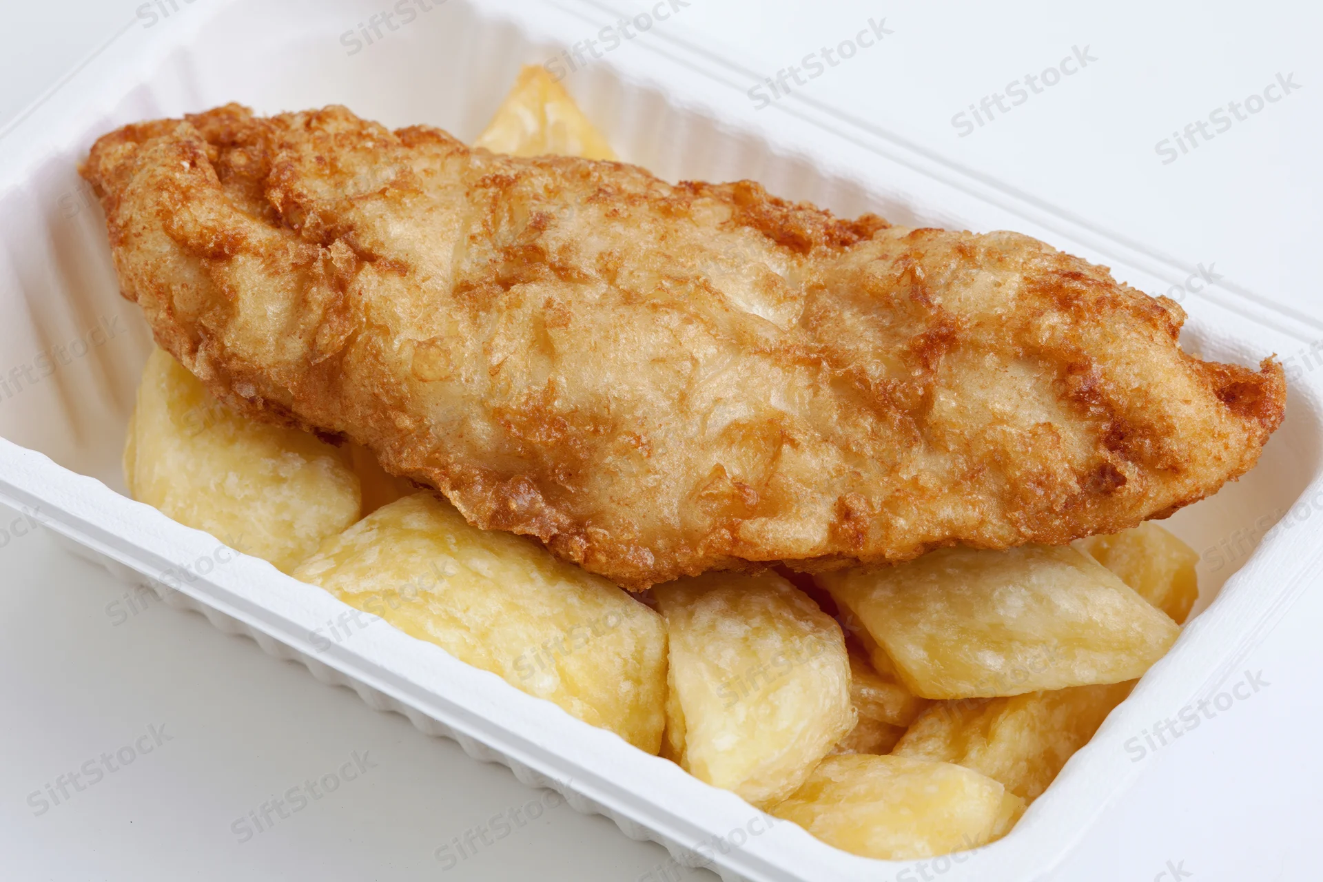 Battered fish fillet resting on thick-cut chips in a white takeaway container