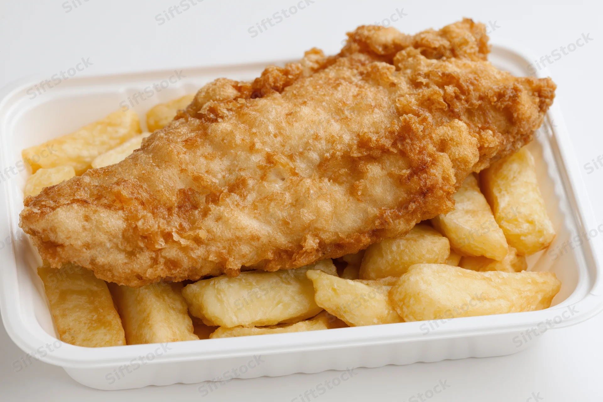 Battered fish fillet resting on thick-cut chips in a white takeaway container