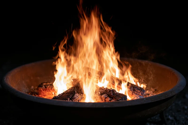 Fire burning in a round metal fire pit at night