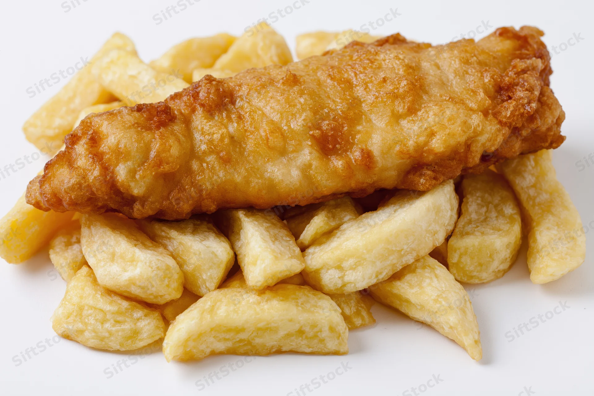 Battered fish fillet resting on thick-cut chips against white background