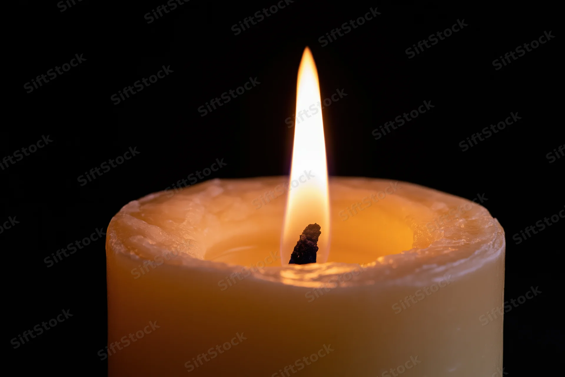 A burning candle with a steady flame centered against a black background