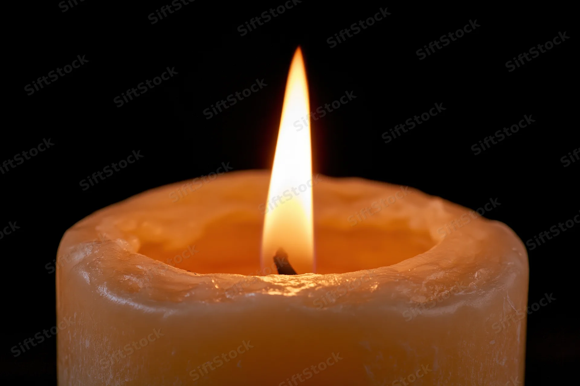 Closeup of a single candle flame burning steadily against a black background