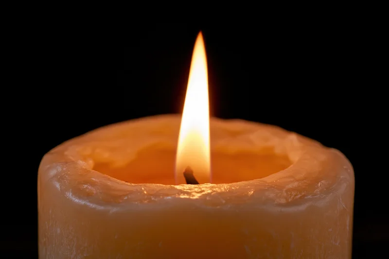 Closeup of a single candle flame burning steadily against a black background
