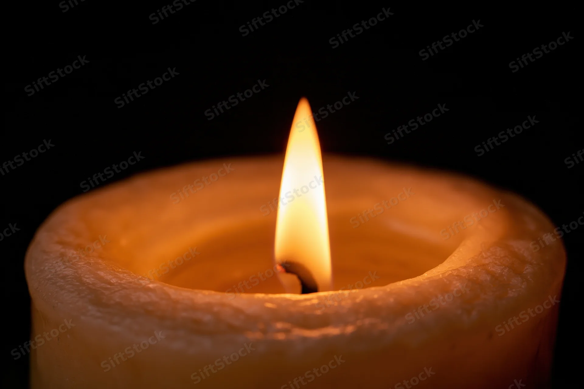 A single candle flame burning steadily against a dark background