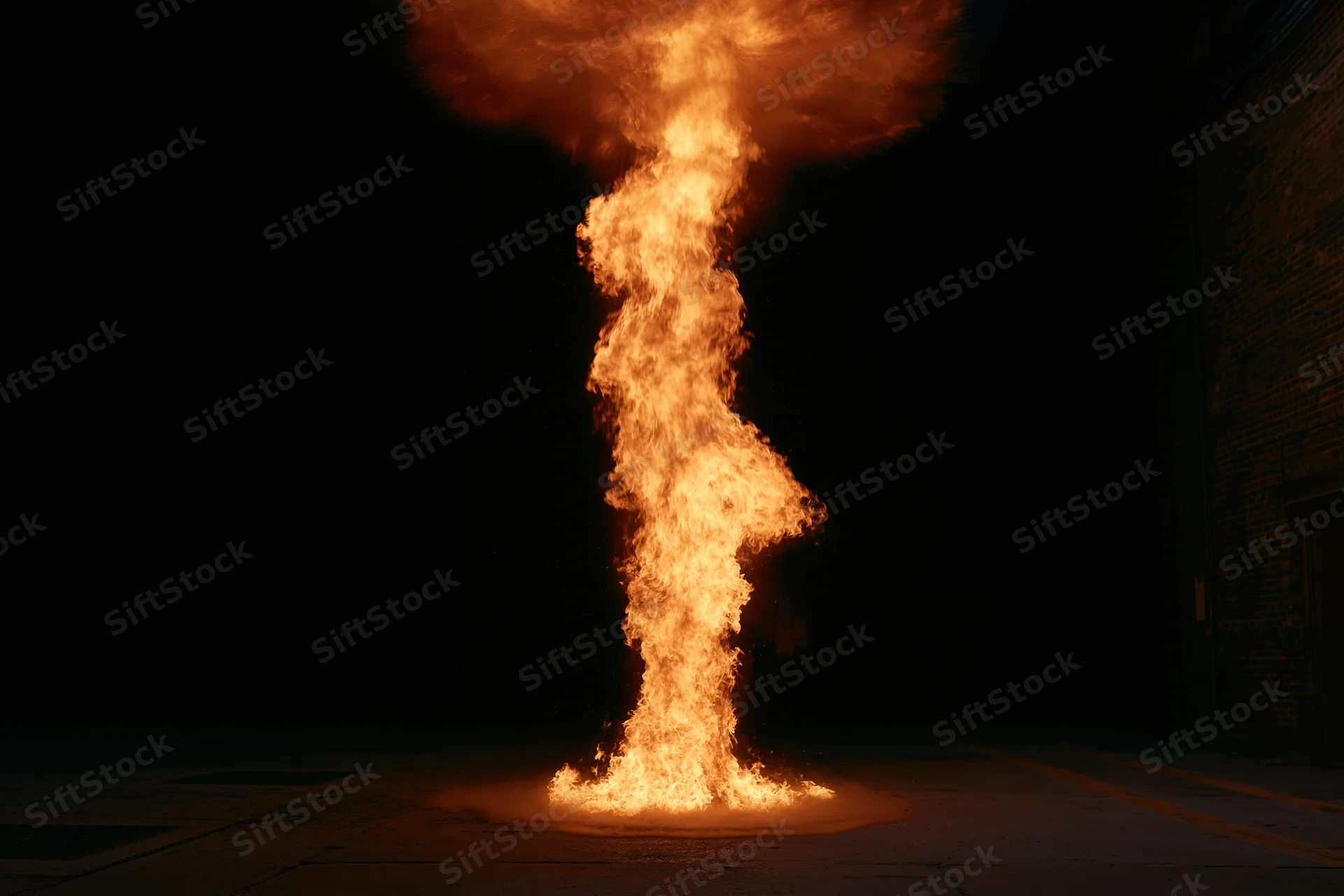 Vertical column of fire rising from pavement in dark urban alley at night