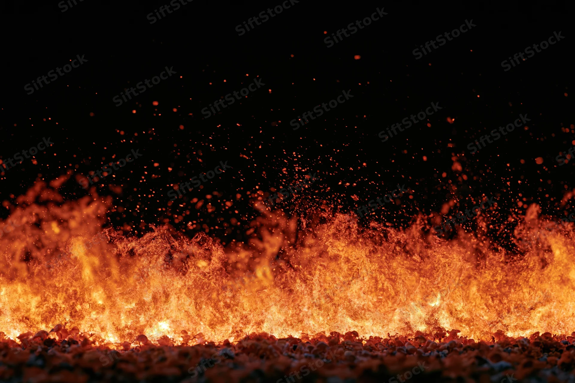 Intense flames rising from ground level against black background