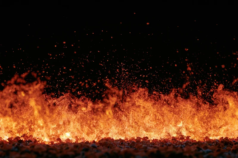 Intense flames rising from ground level against black background