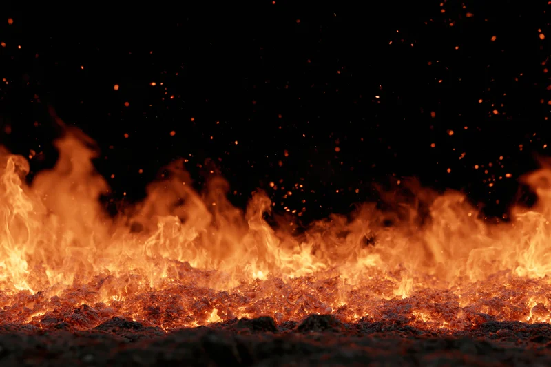 Intense flames burning across a dark ground at night