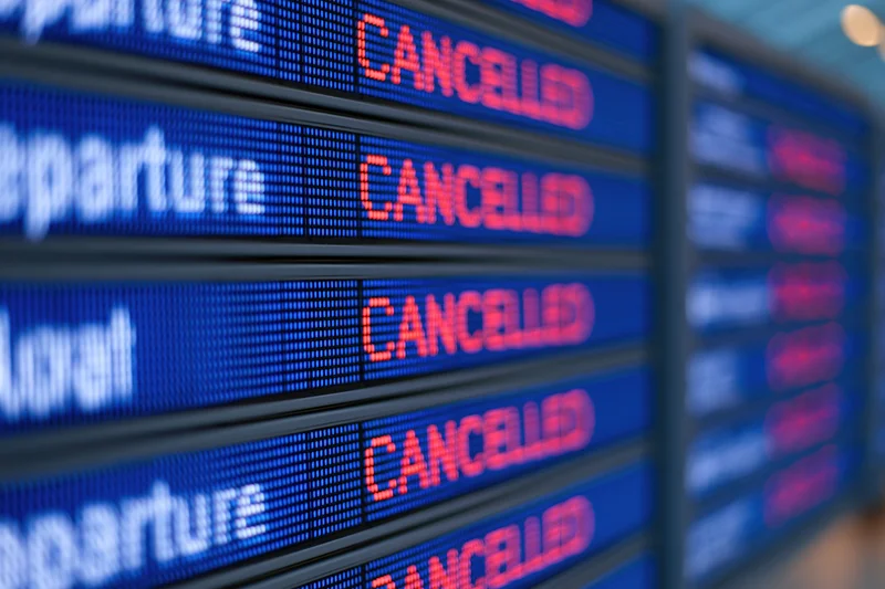 Digital flight information board showing multiple cancelled departures at airport terminal