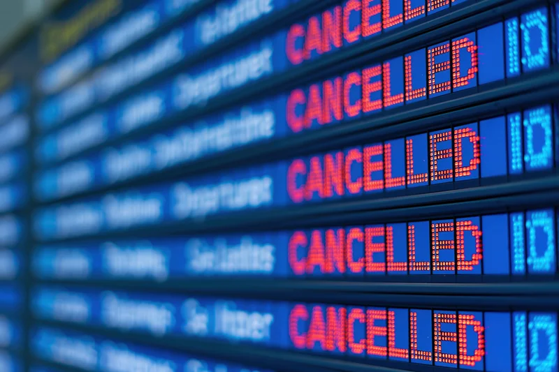 Digital flight information board showing multiple cancelled departures at airport terminal