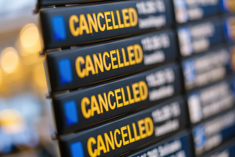 Digital flight information board showing multiple cancelled flights at airport terminal