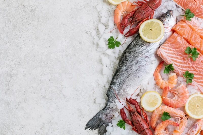 Assorted fresh raw seafood arranged on ice along the right side of a white countertop