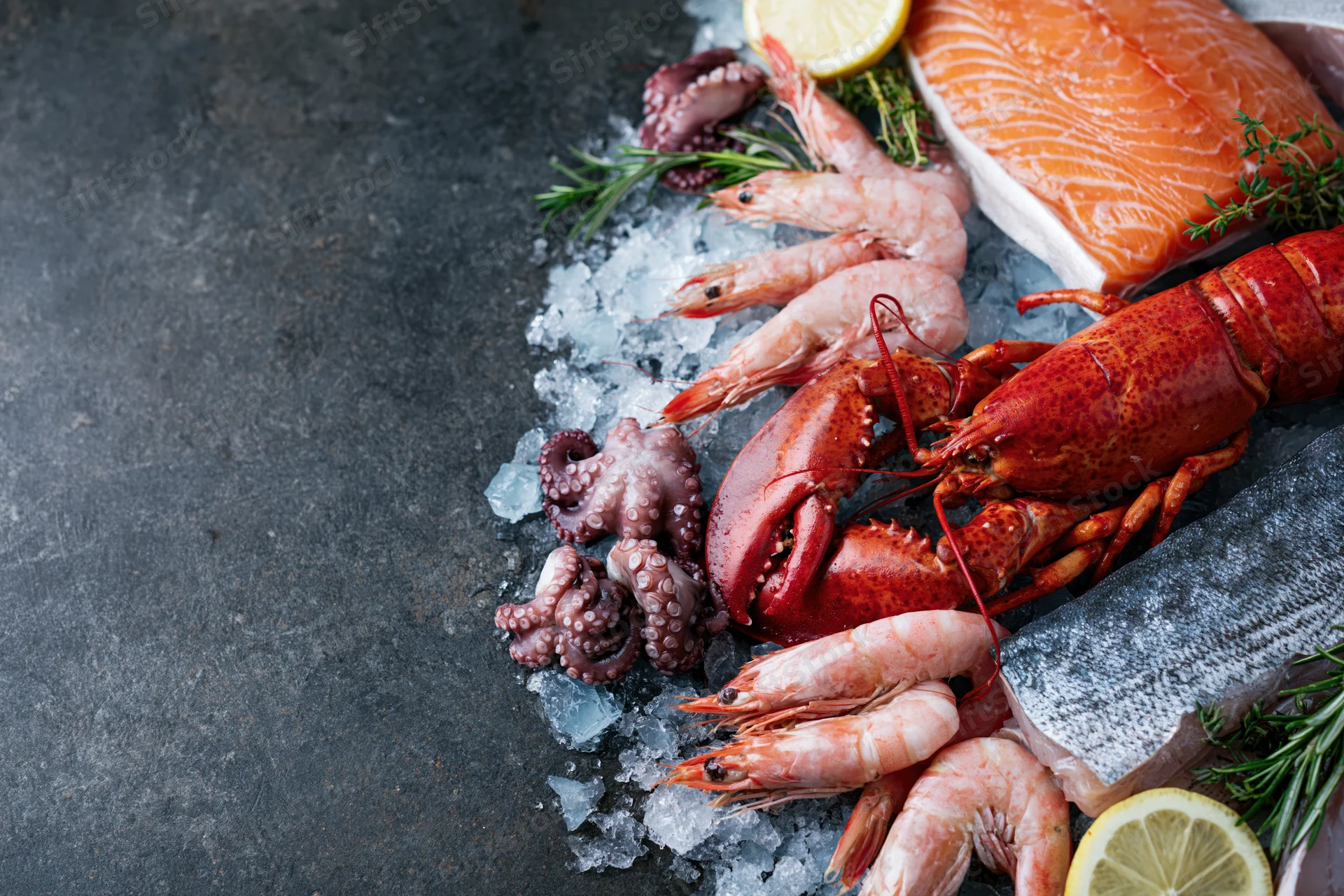 Assorted fresh seafood including salmon, lobster, shrimp, and octopus arranged on crushed ice on a dark surface