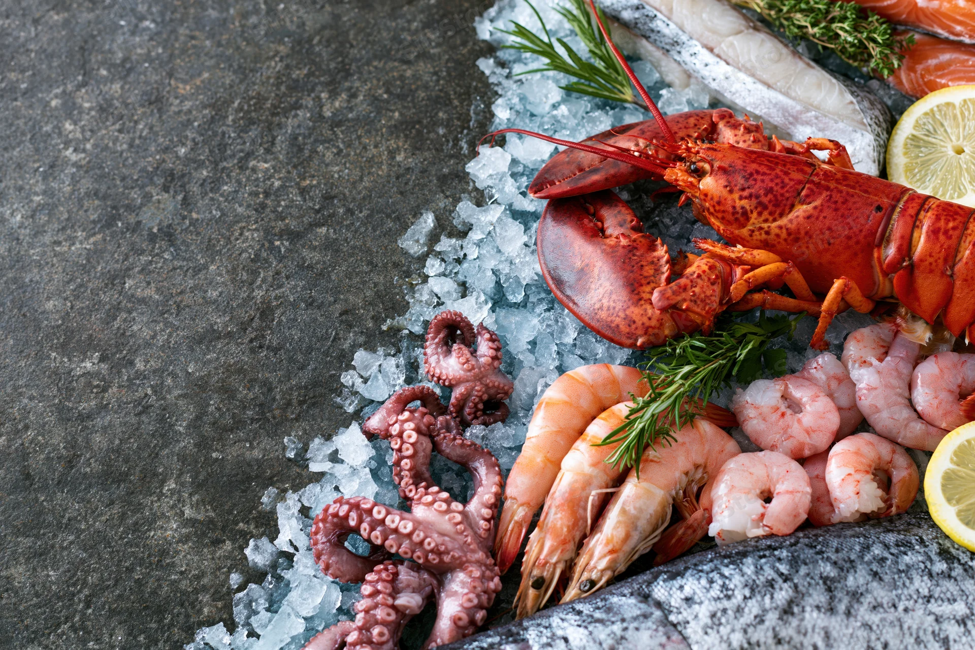 Assorted fresh seafood including lobster, shrimp, octopus and salmon arranged on crushed ice on a stone surface