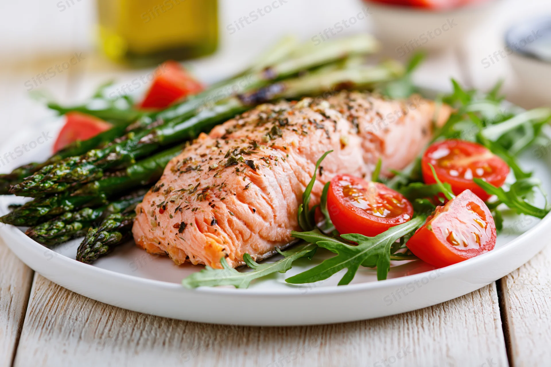 Baked salmon fillet with asparagus and tomatoes on a white plate