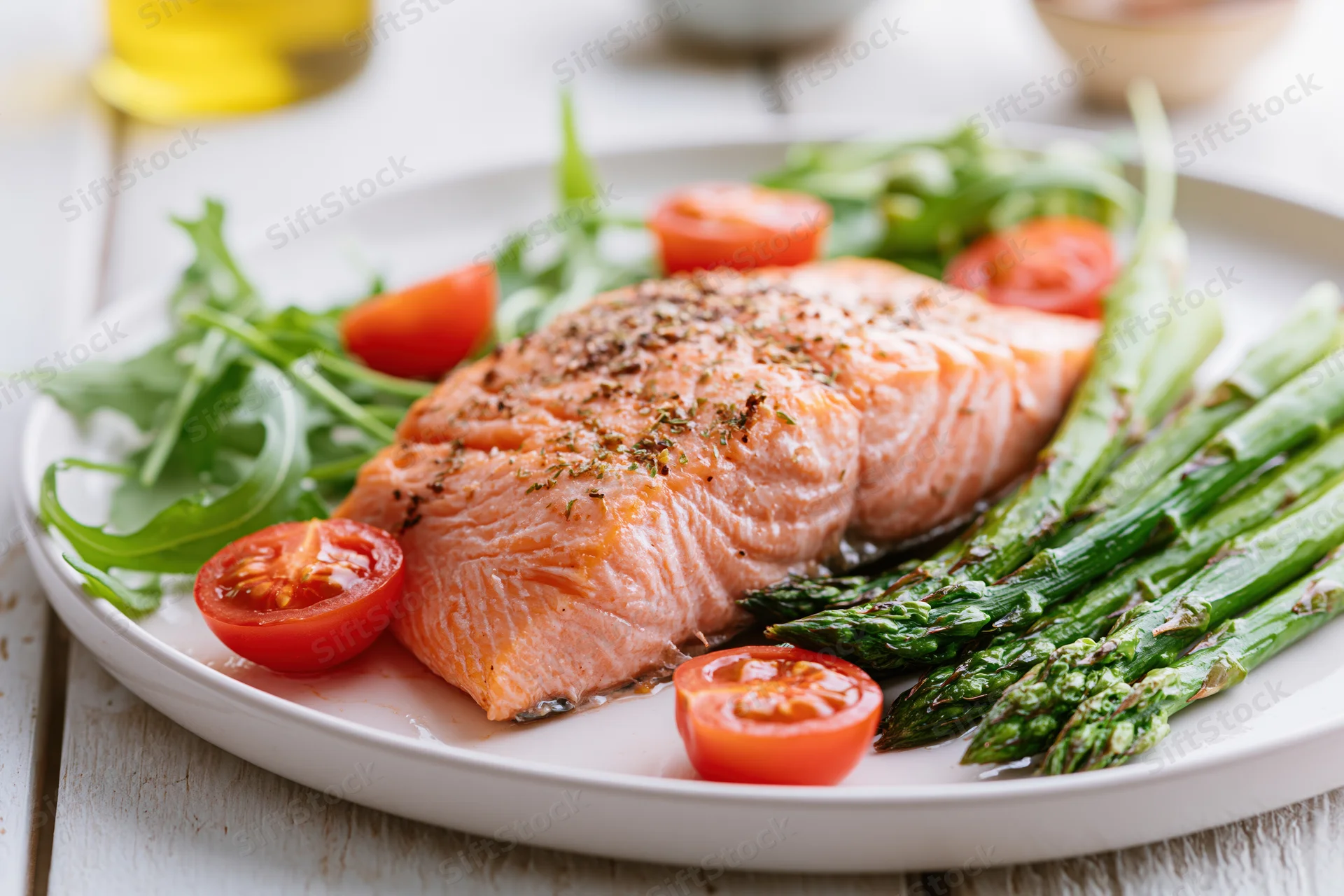 Baked salmon fillet with asparagus and cherry tomatoes on a white plate
