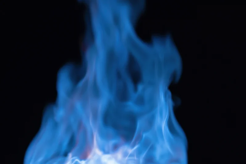 Blue gas flame burning intensely against a pure black background