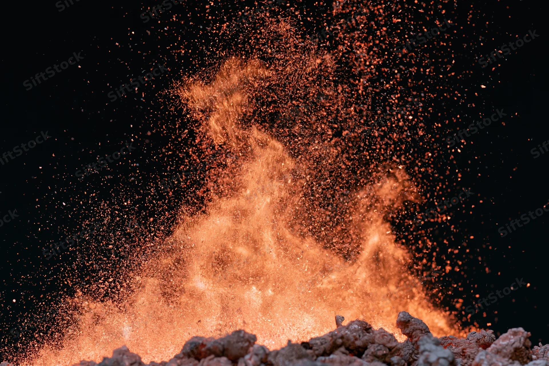 Fiery sparks bursting upward from glowing embers against black background