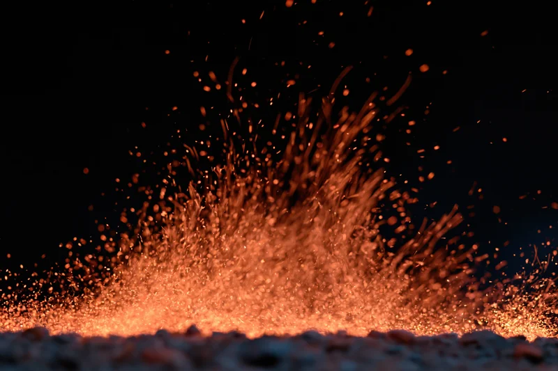 Glowing ember sparks bursting upward from a fire at night